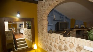 A staircase leading to a living area with a stone wall, a fireplace, and a television. - Rural House La Biblioteca. 6hab=350€- 7hab=390€ (Almagro)