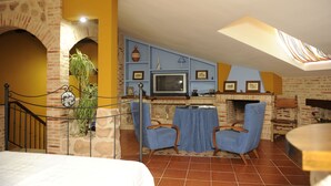 A cozy room with a fireplace, blue chairs, a dining table, and a TV. - Rural House La Biblioteca. 6hab=350€- 7hab=390€ (Almagro)