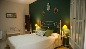 A neatly made bed with a white bedspread and two pillows, flanked by bedside tables with lamps, in a room with green walls and a mirror above the bed. - Rural House La Biblioteca. 6hab=350€- 7hab=390€ (Almagro)