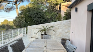 An outdoor patio with a stone wall, a wooden table, and chairs. - Nice architect house with stunning pine view only 4km from Aix en Provence (Saint-Marc-Jaumegarde)