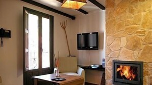 Una habitación acogedora con pared de piedra, chimenea, televisión y zona de comedor con mesa y sillas.