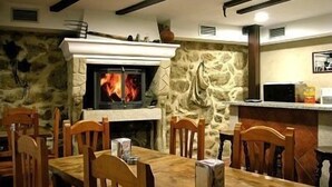 Un comedor con chimenea de piedra, sillas de madera y una mesa.