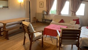 Een gezellige kamer met een houten bankje, een tafel, een slaapbank en een bed.