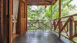 Une véranda en bois offrant une vue sur une végétation luxuriante.