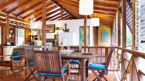 Un intérieur en bois comprenant un coin repas, une cuisine et de grandes fenêtres.