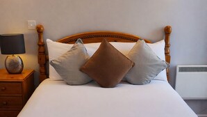 A neatly made bed with a wooden headboard, two bedside lamps, and a bedside table with a lamp. - Aran View Holiday Homes Doolin - The Courtyard House - Sleeps 9 (Doolin)