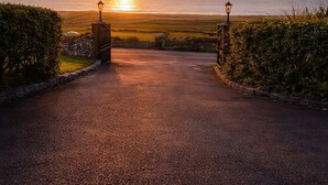 A paved pathway leading to a sunset view over the ocean, with lamp posts on either side. - Aran View Holiday Homes Doolin - The Courtyard House - Sleeps 9 (Doolin)