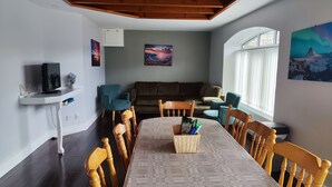 A dining area with a table, chairs, a television, and artwork on the walls. - Aran View Holiday Homes Doolin - The Courtyard House - Sleeps 9 (Doolin)