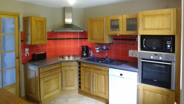 A kitchen with wooden cabinets, a gas stove, a microwave, and a dishwasher. - Holidays House, NORMANDY, Gite in the marshes of Carentan -wifi (Terre-Et-Marais)