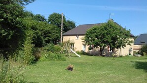 A residential backyard with a swing set, a lawn, and a house with a sloped roof. - Holidays House, NORMANDY, Gite in the marshes of Carentan -wifi (Terre-Et-Marais)