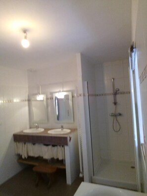 Une salle de bain avec deux lavabos, un miroir, une douche et une baignoire.