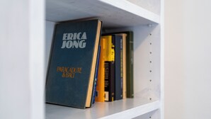 A bookshelf with books, including one titled "ERICA JONG". - Studio in the heart of Finalborgo (Finale Ligure)