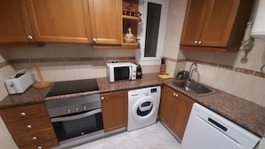 A compact kitchen with wooden cabinets, a microwave, a toaster, a sink, and a dishwasher. - Spectacular Frontline, Pineda de Mar (Pineda de Mar)
