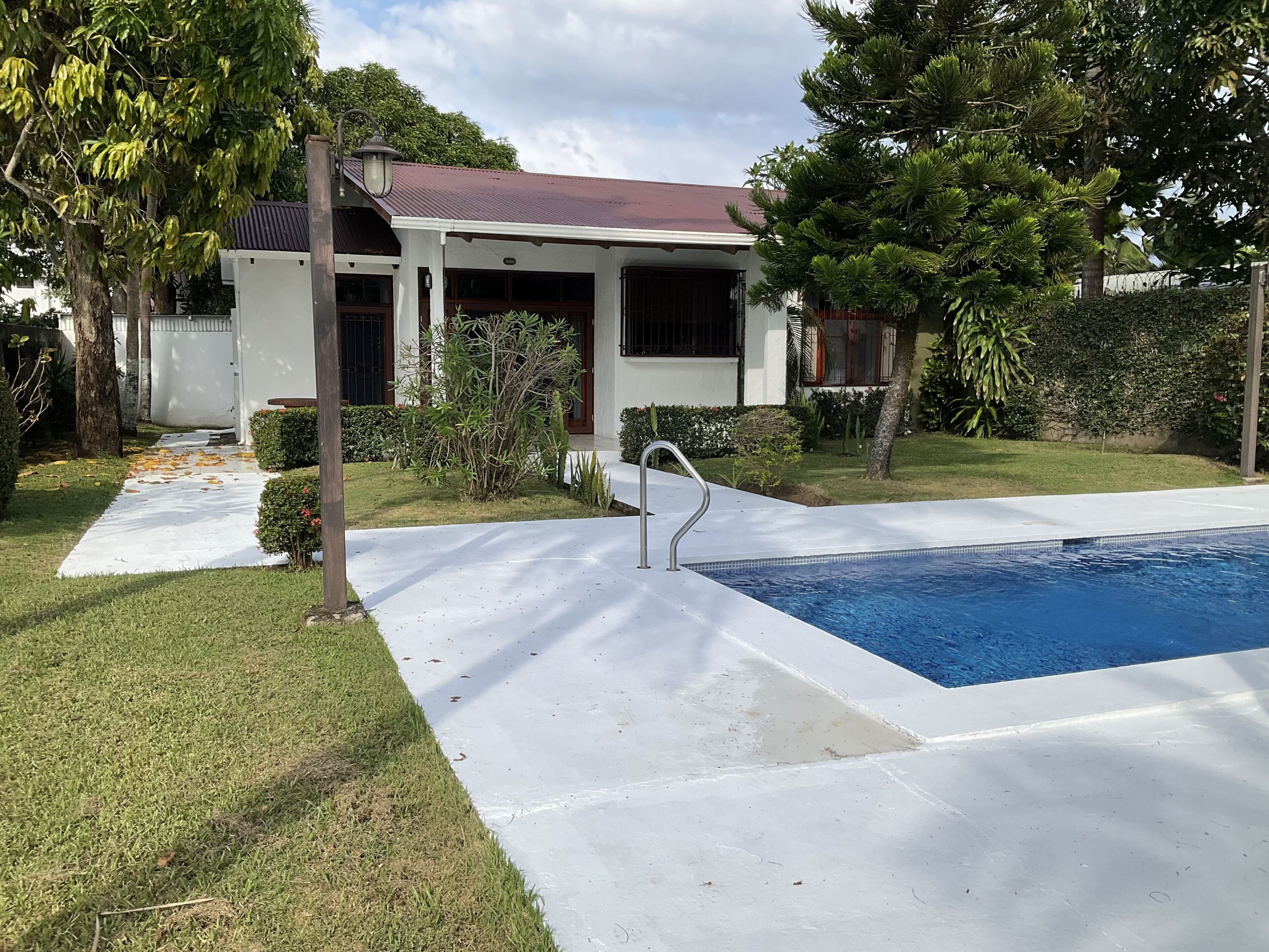 Une propriété résidentielle dotée d’une piscine, d’un patio couvert et d’une pelouse bien entretenue.