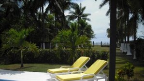 A pool area with lounge chairs and palm trees. - El Roble: villa directly on the beach. (El Roble)