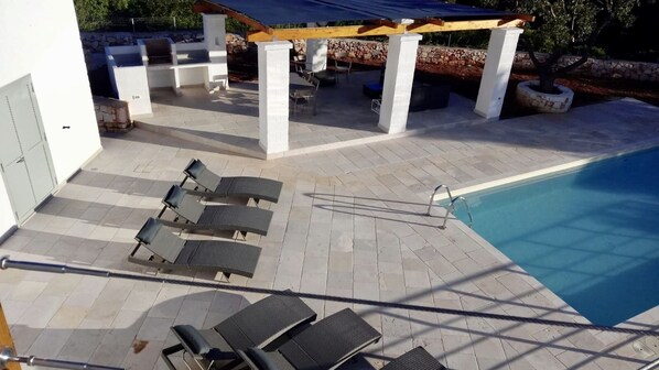 Un espace extérieur avec une piscine, des chaises longues, un barbecue et une pergola.
