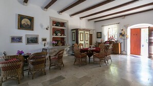 Comedor con mesa de madera, sillas de mimbre, chimenea y puerta roja.