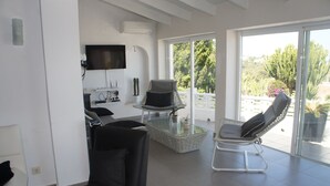 A modern living room with a glass coffee table, a black sofa, and a reclining chair. - House with panoramic views towards the sea and mountains  (Dénia)