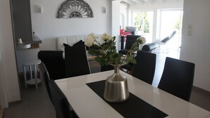 A dining area with a white table, black chairs, a vase with white flowers, and a decorative wall piece. - House with panoramic views towards the sea and mountains  (Dénia)