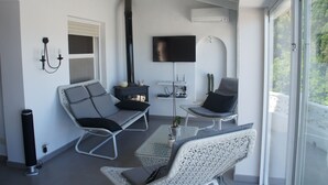 A modern living room with a flat-screen TV, a fireplace, and a balcony with a view. - House with panoramic views towards the sea and mountains  (Dénia)