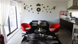 Een moderne woonkamer met een zwart-wit gestreepte bank, twee rode fauteuils, een ronde salontafel en een zwart-wit tapijt.