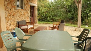 A stone building with a patio area featuring a table and chairs. - Le Rosier, Gîtes de Peyrounou. Spacious 2 bedroom gîte. (Lacapelle Biron)