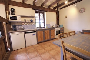 Une cuisine avec des meubles de rangement en bois, un four à micro-ondes, un grille-pain, un évier et une table à manger avec des chaises.