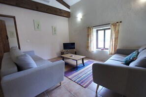 A living room with two sofas, a coffee table, a TV, and a window with curtains.