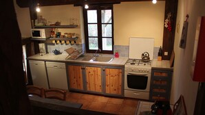A compact kitchen with a sink, stove, and microwave. There are wooden cabinets and a window above the sink. - Le Rosier, Gîtes de Peyrounou. Spacious 2 bedroom gîte. (Lacapelle Biron)