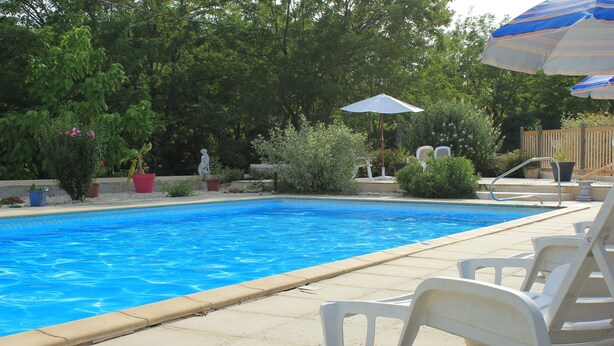 A swimming pool with a tiled edge, surrounded by potted plants and a wooden fence. - Le Rosier, Gîtes de Peyrounou. Spacious 2 bedroom gîte. (Lacapelle Biron)