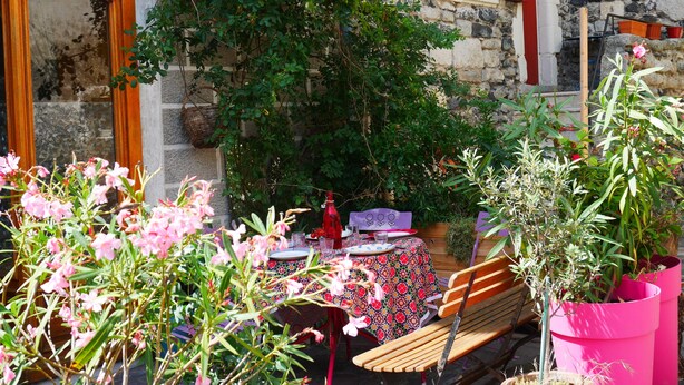 An outdoor seating area with a table and chairs, surrounded by plants and flowers.