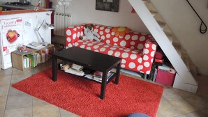 A cozy living room with a red polka dot sofa, a black coffee table, and a red rug.