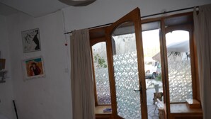 A room with a sliding glass door leading to an outdoor area, a small bench, and a tiled floor.