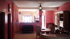 A dining area with a table and chairs, a hanging light fixture, and a window with curtains. - Aourir: House / Villa - Aourir (Aourir)