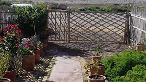 A garden pathway leading to a beach with potted plants and a wooden lattice gate. - Aourir: House / Villa - Aourir (Aourir)