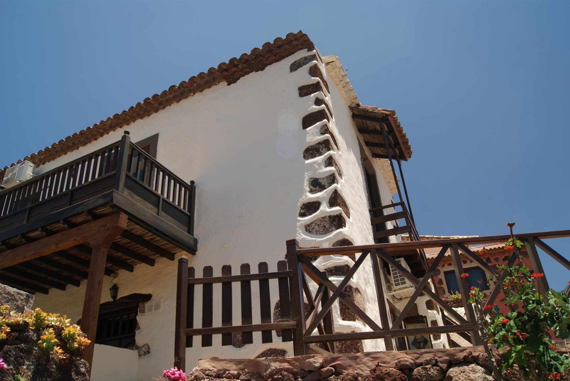 Ein traditionelles Gebäude mit weißer Fassade, einem hölzernen Balkon und einer Wand aus Stein.