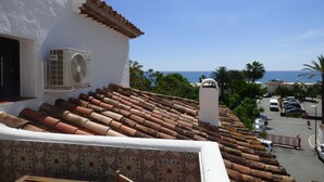 Un bâtiment blanc avec des tuiles en terre cuite sur le toit et un balcon carrelé.