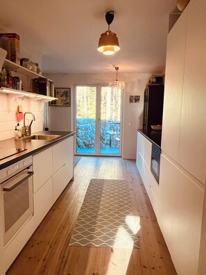 A modern kitchen with wooden flooring, white cabinets, a built-in oven, and a pendant light. - Top class house in the Stockholm archipelago 45 mins from City - car or bus (Stavsnäs)
