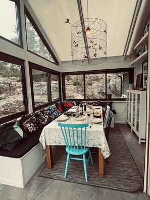 A dining area with a table set for two, a blue chair, and a birdcage with lights above. - Top class house in the Stockholm archipelago 45 mins from City - car or bus (Stavsnäs)