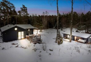 A cabin with a large deck and a covered outdoor area, surrounded by a snowy forest. - Top class house in the Stockholm archipelago 45 mins from City - car or bus (Stavsnäs)