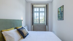 Ein Schlafzimmer mit Bett, Kopfstütze, Fenster und einem Wandbild.
