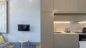 Eine kompakte Küche mit Einbauofen, Toaster und Spüle. Ein kleiner Tisch mit einer Glasvase und einem Stuhl.