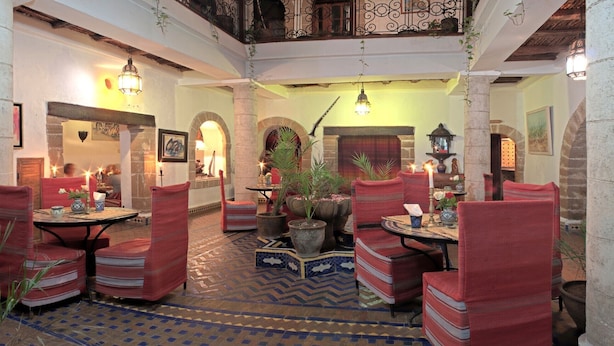 A cozy lobby with red upholstered chairs, a patterned floor, and a central fountain. - Room 1 - 18th century riad in the center of essaouira medina (Marrakech-Safi)