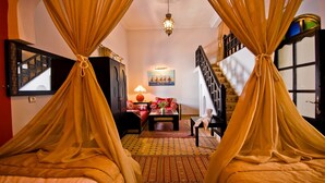 A room with a bed, a sofa, a table with a vase, a painting, and a staircase. - Room 1 - 18th century riad in the center of essaouira medina (Marrakech-Safi)