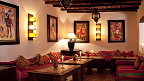 A cozy lounge area with patterned sofas, a wooden coffee table, and wall-mounted lamps. - Room 1 - 18th century riad in the center of essaouira medina (Marrakech-Safi)