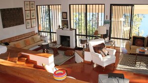A spacious living room with a fireplace, large windows, and a view of the outdoors.