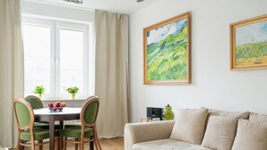 Una sala acogedora con un sofá beige, una mesa de comedor con sillas y dos cuadros en la pared.