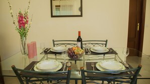 Une table à manger dressée avec des assiettes, une bouteille de vin et un panier de fruits.