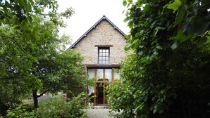 Una casa in pietra con una porta e finestre in legno, immersa nel verde.