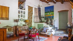 Una sala de estar acogedora con techo de madera, una mesa de comedor con sillas, un sofá y un cuadro de pájaros.